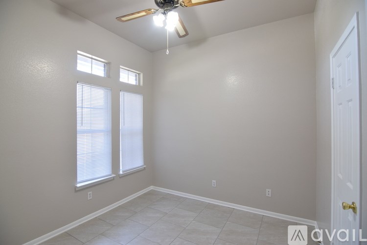 A room with a ceiling fan and two windows.
