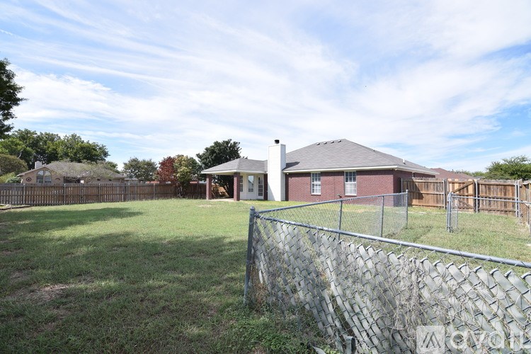 A house with a grey roof and a fence in front of it.