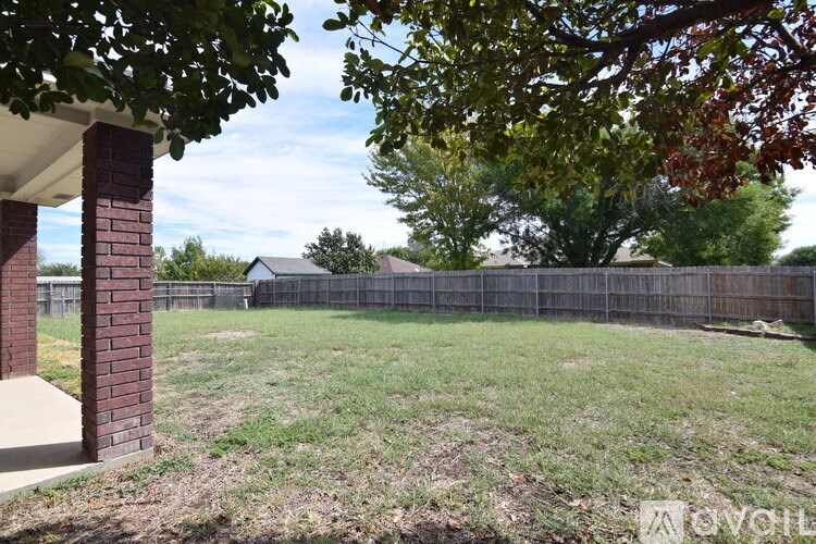 A backyard with a fence and a tree.