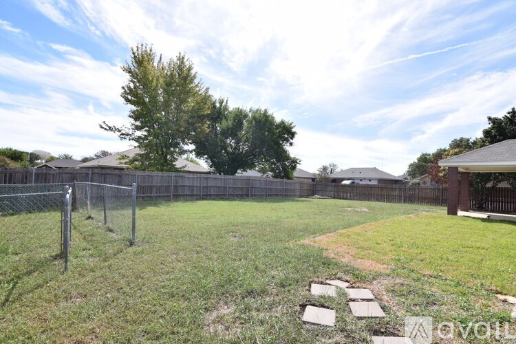 A backyard with a fence, a tree, and a small garden.