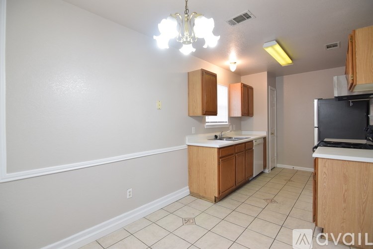 A kitchen area with a sink, cabinets, and a refrigerator.