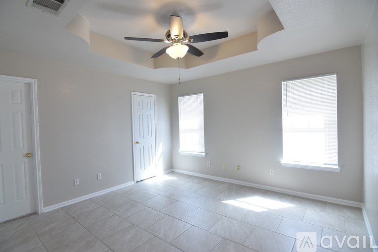 A room with a ceiling fan and two windows.