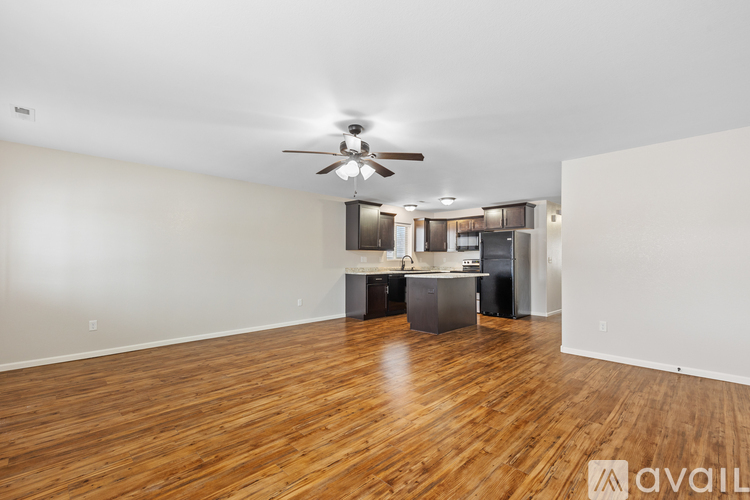 A spacious room with wooden floors and a ceiling fan.