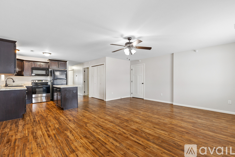 A spacious room with wooden flooring and a ceiling fan.