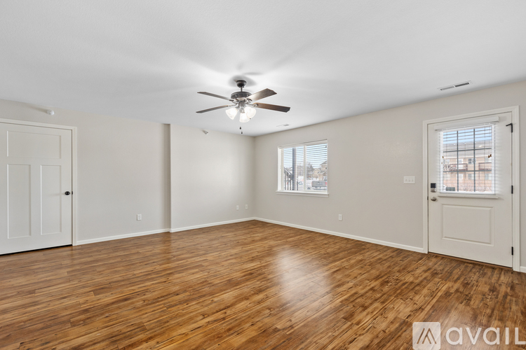 A spacious room with wooden floors and a ceiling fan.