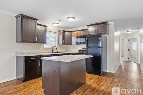 A kitchen with dark wood cabinets and a black refrigerator.