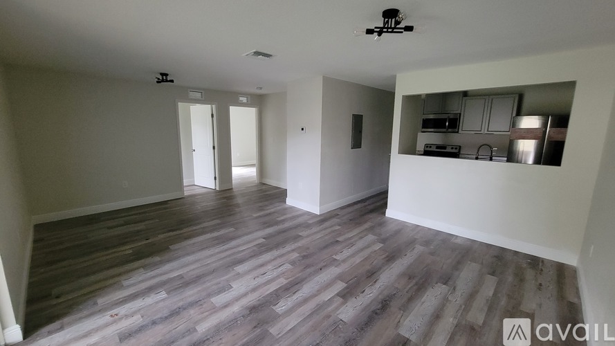 A spacious room with wooden flooring and white walls.