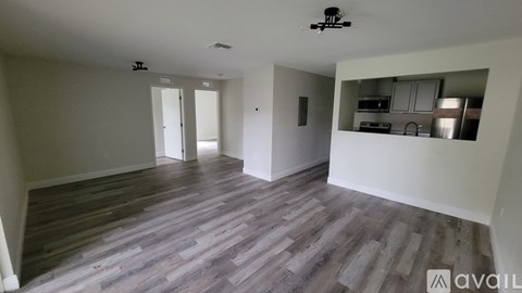 A spacious room with wooden flooring and white walls.