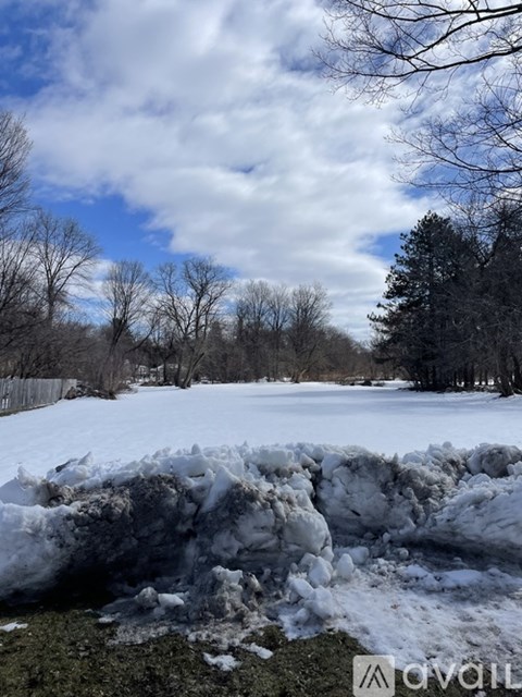 A snow-covered field with trees in the background.