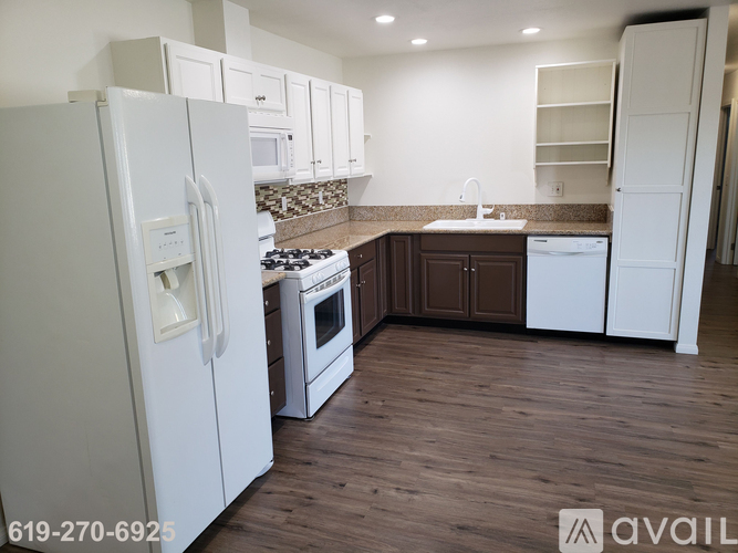 A kitchen with white appliances and wooden floors.