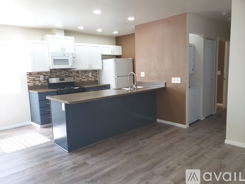 A kitchen with white appliances and wooden floors.