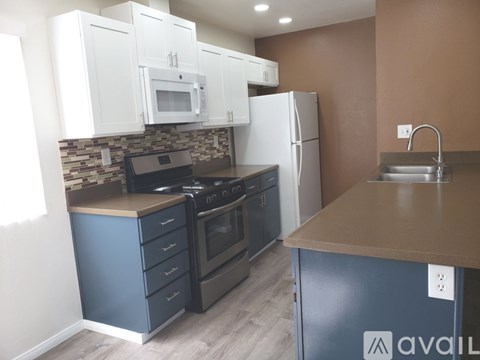 A kitchen with white cabinets and a countertop with a microwave and oven.