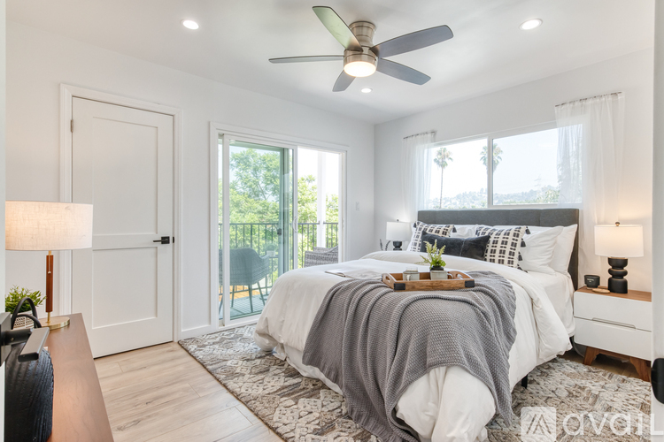 A bedroom with a bed covered in a grey blanket and a ceiling fan.