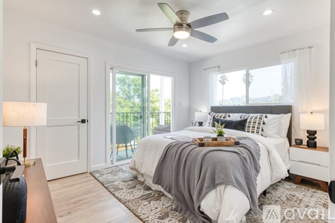 A bedroom with a bed covered in a grey blanket and a ceiling fan.