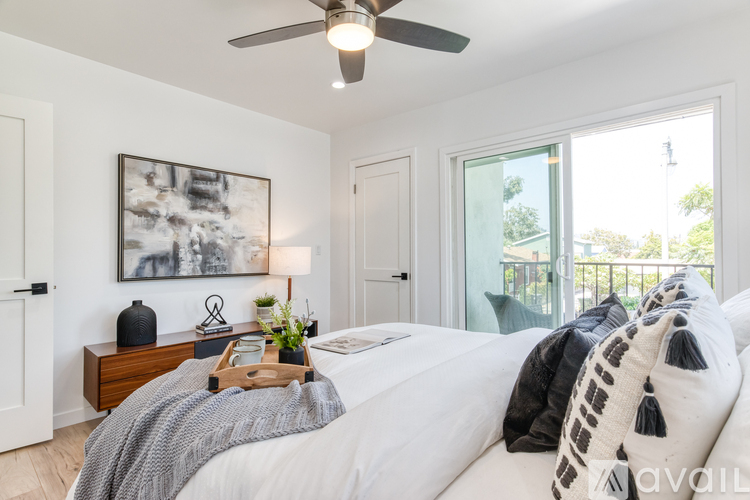 A bedroom with a large bed, a ceiling fan, and a painting on the wall.