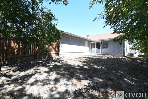 A backyard with a fence and a house in the background.