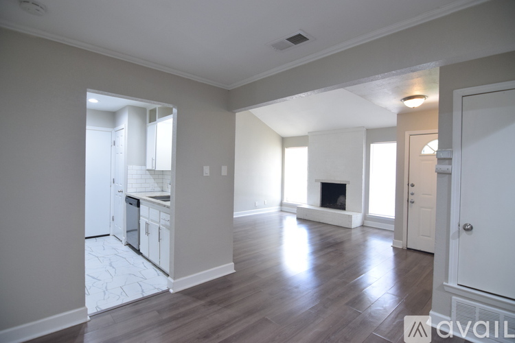 A spacious room with wooden flooring and white walls.