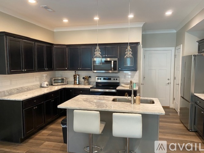 A kitchen with black cabinets and a marble island.