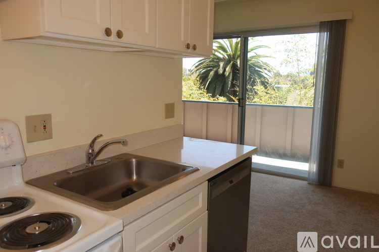 A kitchen with a stove top oven, sink, and a window with a view of the outdoors.