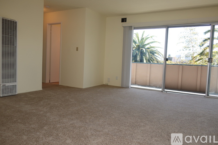 A room with a carpeted floor, a sliding glass door, and a wall-mounted air conditioning unit.