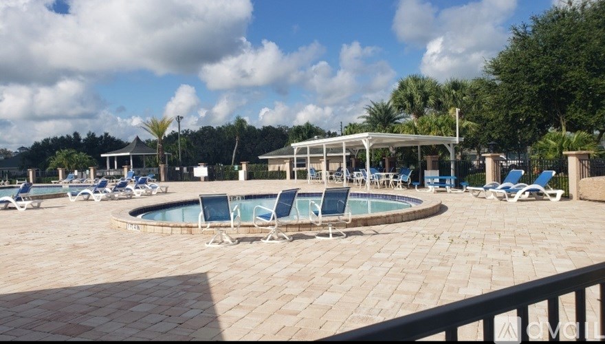 A pool area with sun loungers and a white canopy.
