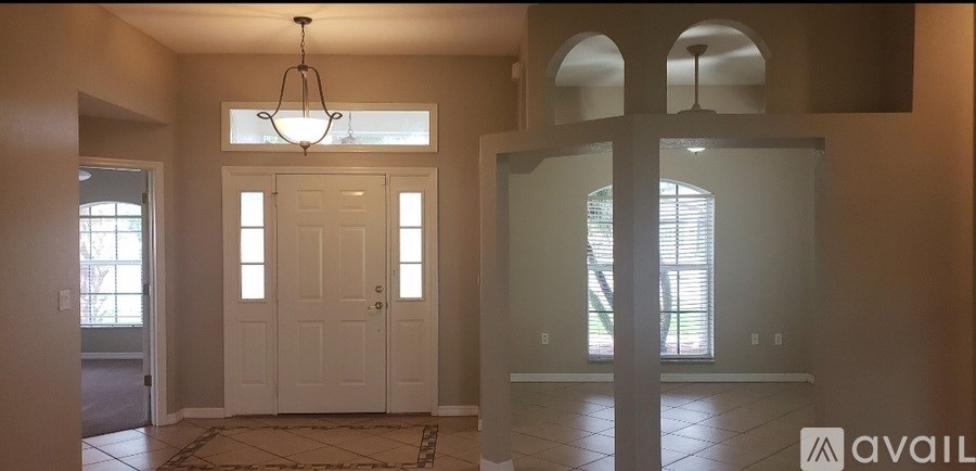 A foyer with a white door and a chandelier.