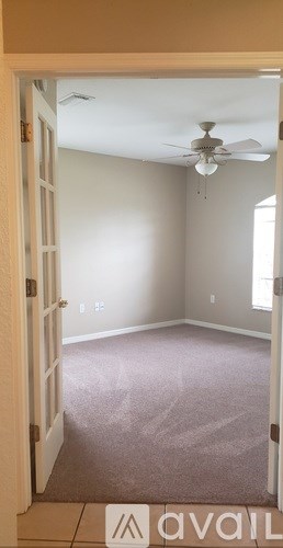 A room with a carpeted floor and a ceiling fan.