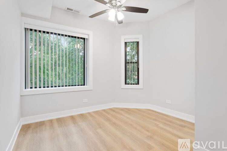 A room with a ceiling fan and two windows.