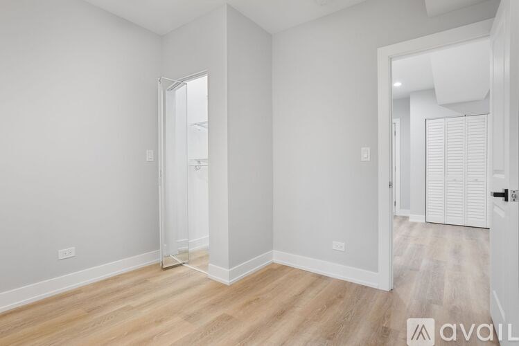 A spacious room with wooden flooring and white walls.