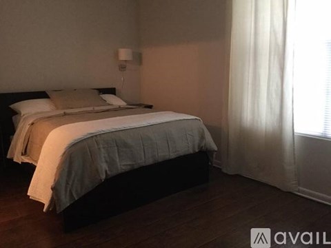 A bedroom with a bed, pillows, and a lamp.