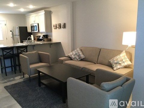 A modern living room with a grey couch and a kitchen area in the background.