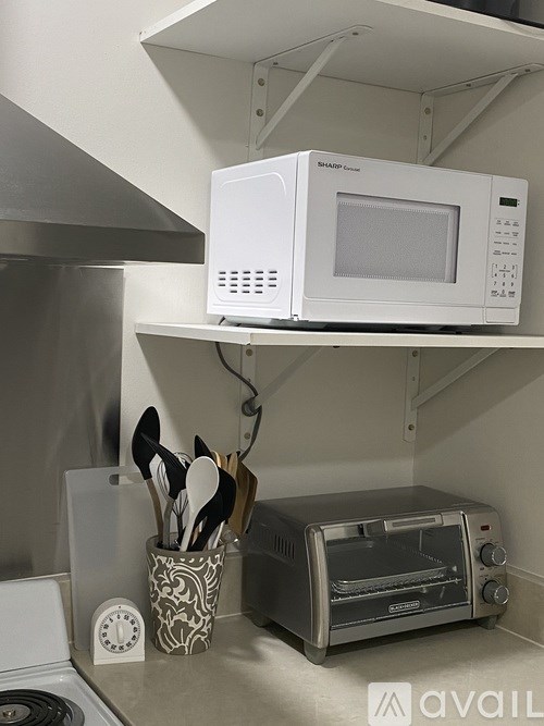 A white microwave oven is mounted on a wall above a toaster oven.