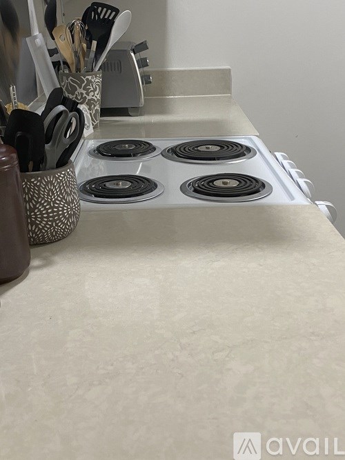 A kitchen counter with a stove top and utensils in a holder.