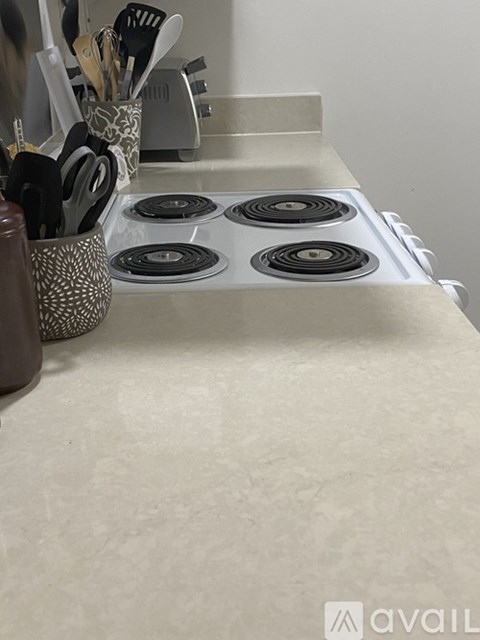A kitchen counter with a stove top and utensils in a holder.