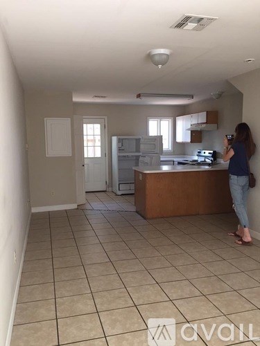A woman is standing in a kitchen with a counter and cabinets.
