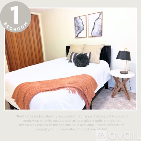 A bedroom with a bed, pillows, a blanket, and a side table.