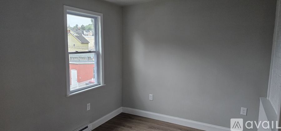A room with a window showing a view of a red building outside.