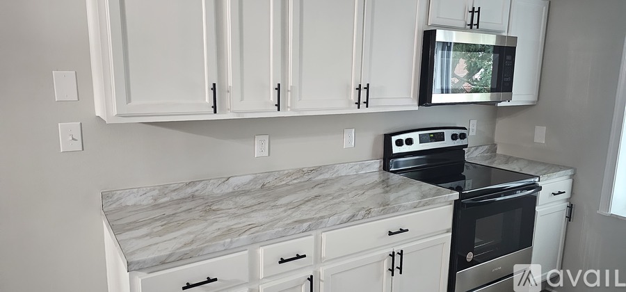 A kitchen with white cabinets and a marble countertop.