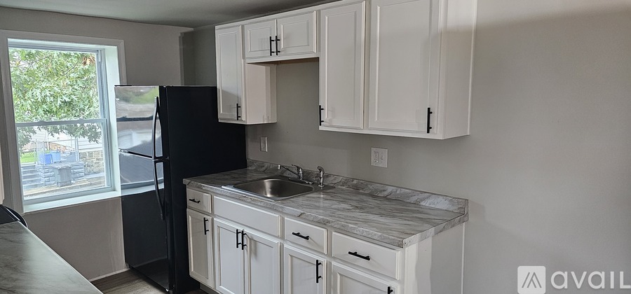 A kitchen with white cabinets and a black refrigerator.