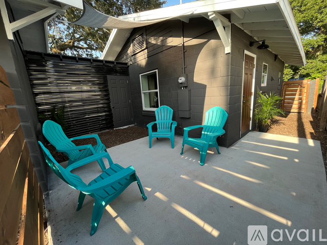 A patio with a white roof and a black wall with a sliding door.