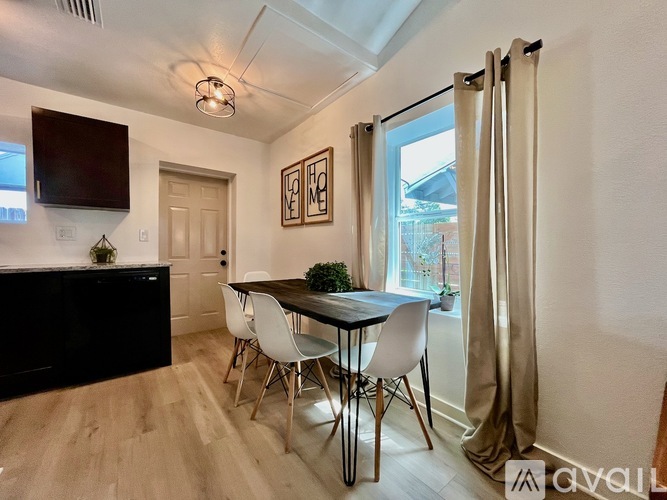 A dining room with a table set for two and a television mounted on the wall.