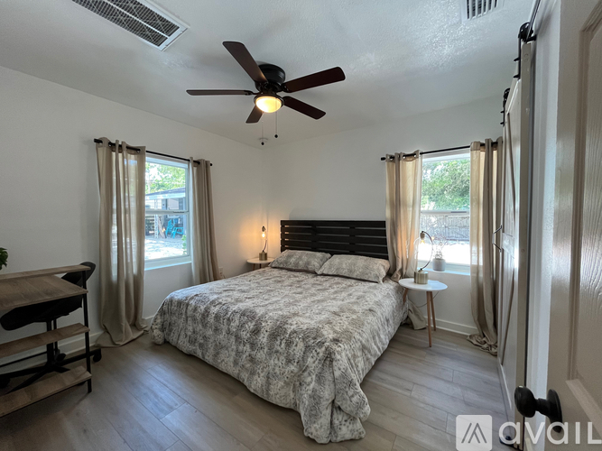 A bedroom with a bed, a ceiling fan, and a window with curtains.