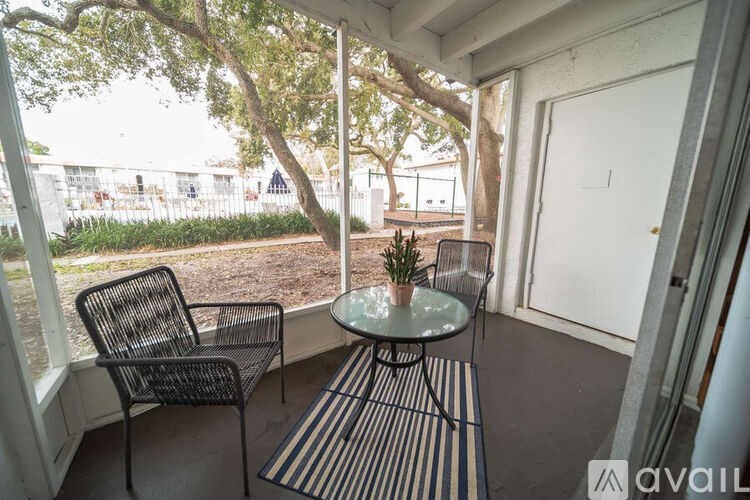 A balcony with a chair, table and potted plant.
