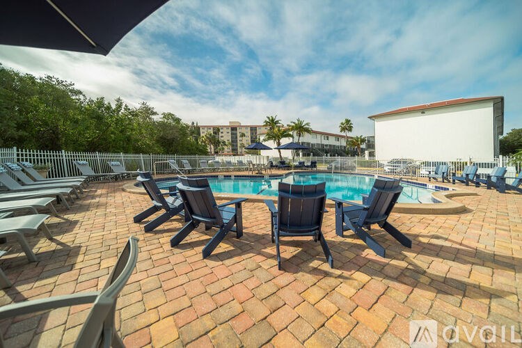 A poolside area with chairs and a building in the background.