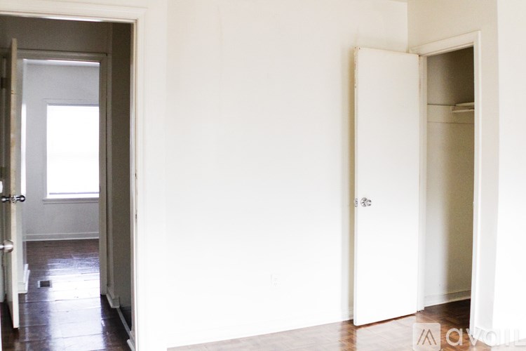 A white door is open to a room with a wooden floor.