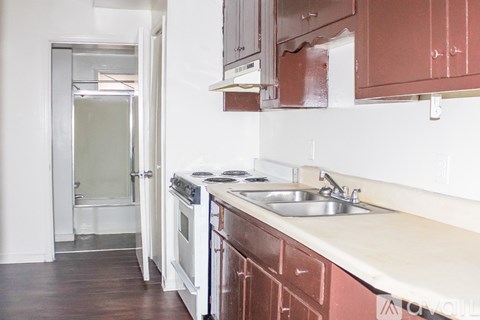 A kitchen with brown cabinets and a white sink.