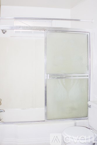 A white toilet sits next to a white bathtub with a glass shower door.
