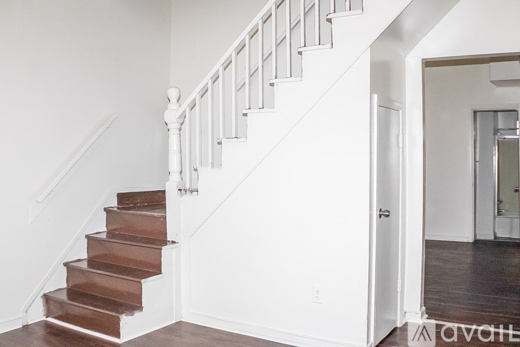 A staircase with white railings and brown steps leads to a hallway.