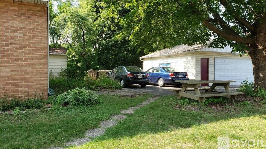 A backyard with a picnic table, a tree, and a car.