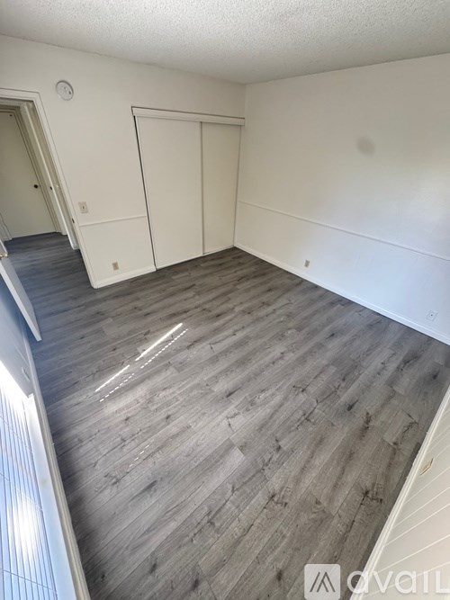A room with wooden flooring and white walls.